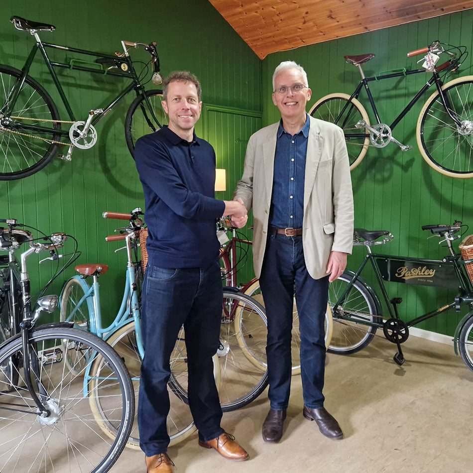 Andy Smallwood shaking hands with Adrian Williams surrounded by Pashley classic bicycles.