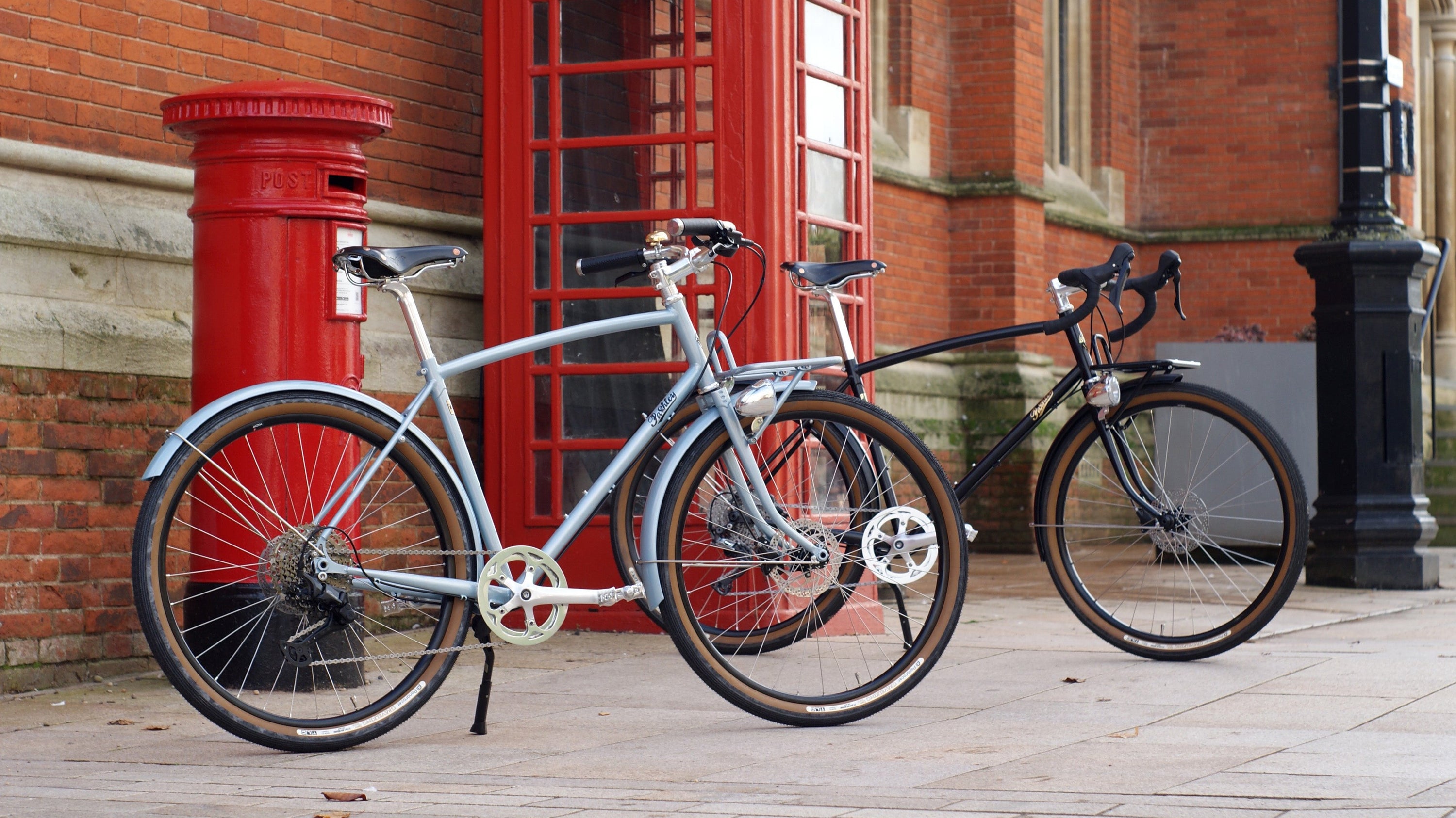 a pair of prospero bicycles next to a red phonebox