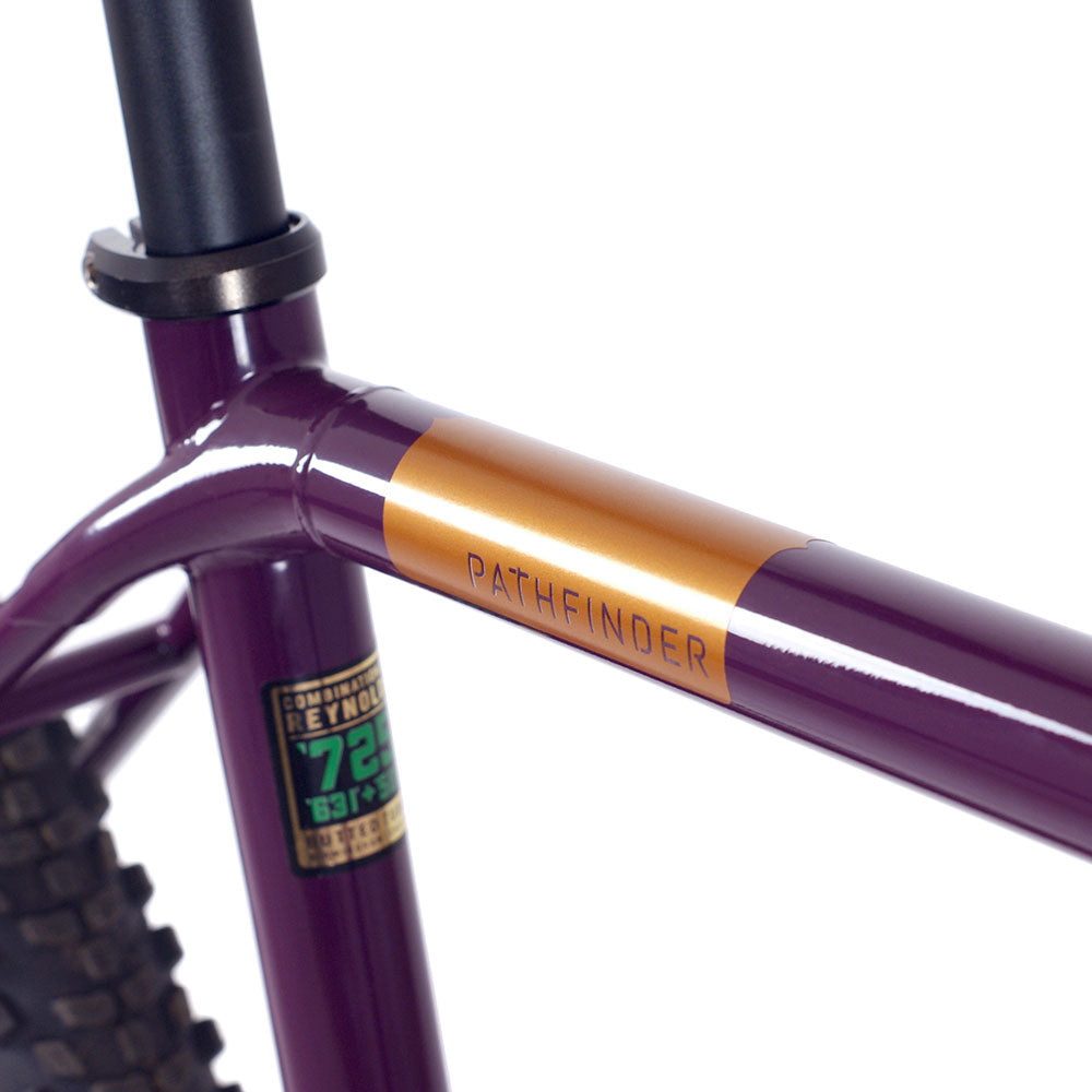 Close-up of bronze pathfinder decal on top tube of purple bike frame.