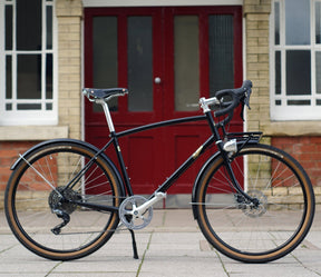 A black Prospero bicycle next to a red door