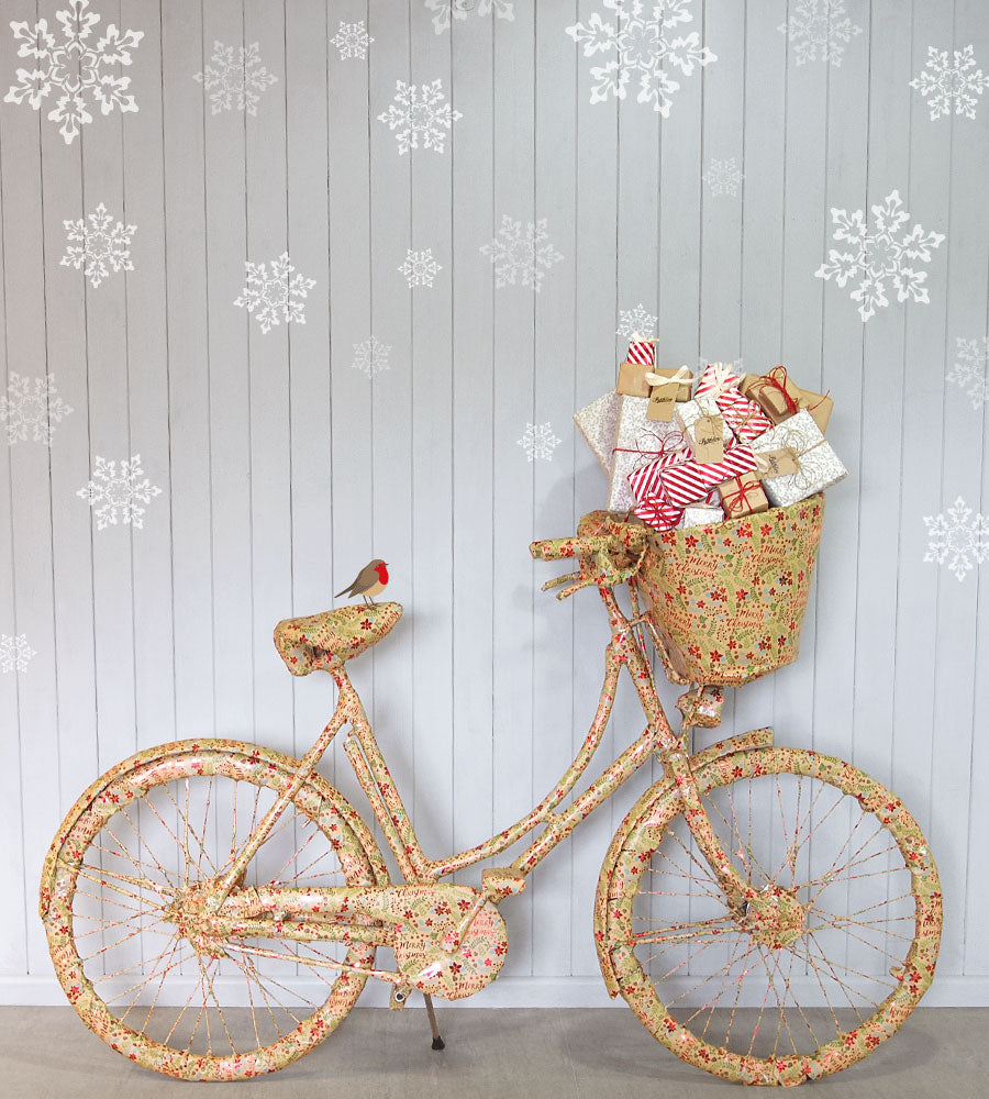 A Pashley bicycle wrapped in Christmas wrapping paper, with Christmas presents in its basket.